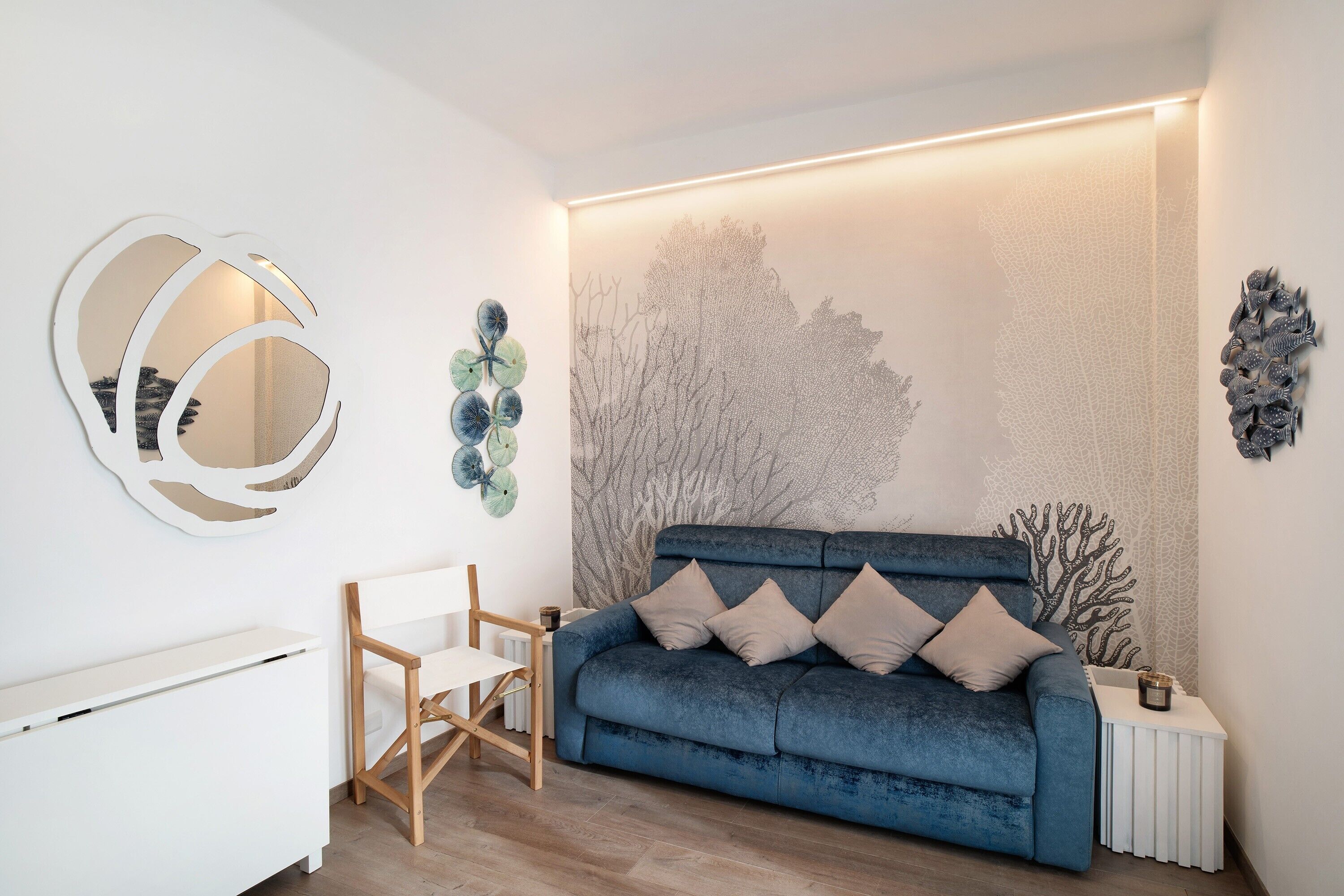 A modern living room with a blue sofa, white side table, and a wall-mounted abstract art piece.