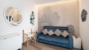 A modern living room with a blue sofa, white side table, and a wall-mounted abstract art piece. - Apartment 'Casa Federica' with Balcony and Wi-Fi (Alassio)