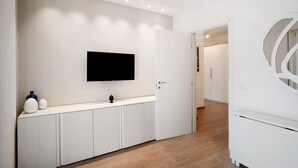 A hallway with a flat-screen TV mounted on the wall, a white console table with decorative items, and a door leading to another room. - Apartment 'Casa Federica' with Balcony and Wi-Fi (Alassio)
