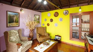 Una sala de estar con un sofá, un sillón, una mesita de centro y platos decorativos en la pared.