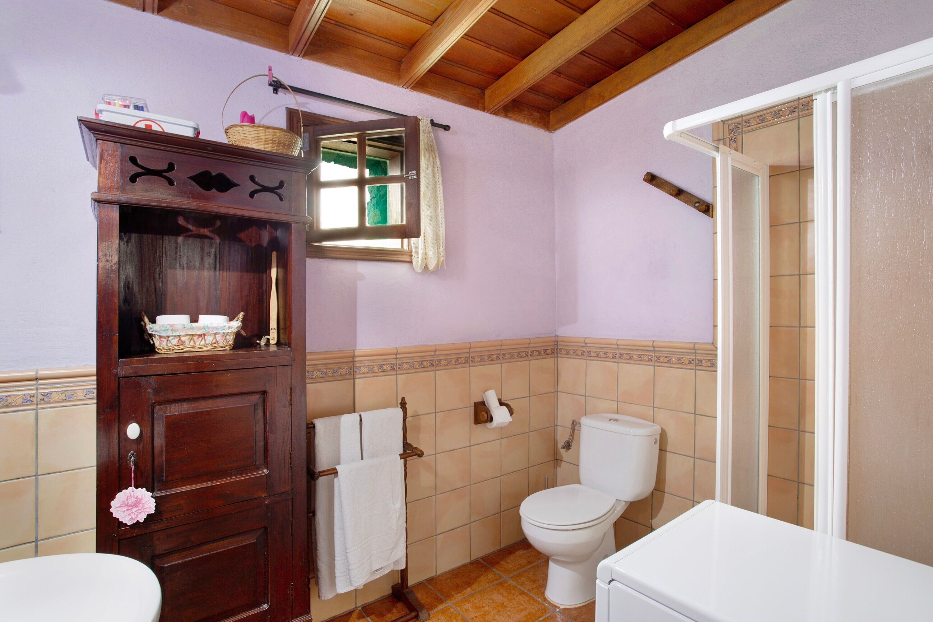 Une salle de bain avec un meuble en bois, des toilettes et un espace douche.