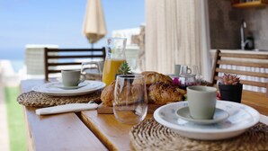 A wooden table with plates, cups, a glass, and a basket of bread, set outdoors with a view. - Holiday Home 'Valista' with Sea View, Private Pool and Wi-Fi (Tijarafe)