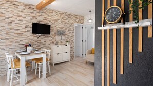 A modern kitchen with a stone backsplash, wooden beams, a flat-screen TV, a dining table with chairs, and a white cabinet. - Holiday Home 'Valista' with Sea View, Private Pool and Wi-Fi (Tijarafe)