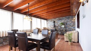 Un espace repas doté d’un plafond en bois, d’un mur en pierre et d’une cheminée.