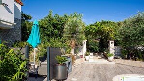 A pool area with a wooden deck, a blue umbrella, and potted plants. - Apartment 'Lucerta Bella' with Shared Pool, Wi-Fi and Air Conditioning (Aix-en-Provence)