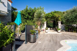 A pool area with a wooden deck, a blue umbrella, and potted plants. - Apartment 'Lucerta Bella' with Shared Pool, Wi-Fi and Air Conditioning (Aix-en-Provence)