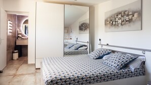 Ein Schlafzimmer mit einem Bett, einem großen Spiegel und einem an der Wand hängenden Kunstwerk.
