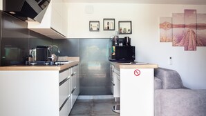 Eine kleine Küche mit Herd, Mikrowelle und Kaffeemaschine. An der Wand hängen drei Bilder in Rahmen.