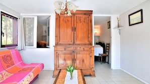 A living room with a wooden cabinet, a pink sofa, and a vase with flowers on a table.