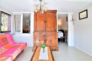 A living room with a wooden cabinet, a pink sofa, and a vase with flowers on a table.