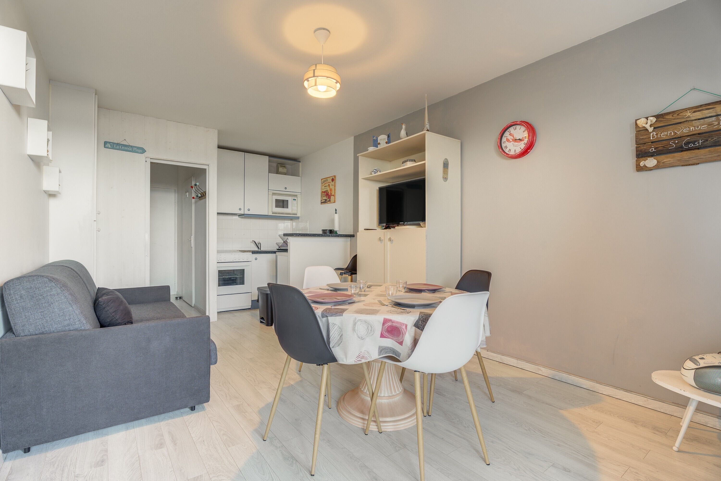 A modern kitchen with white cabinets, a microwave, and a dining area with a table set for four.