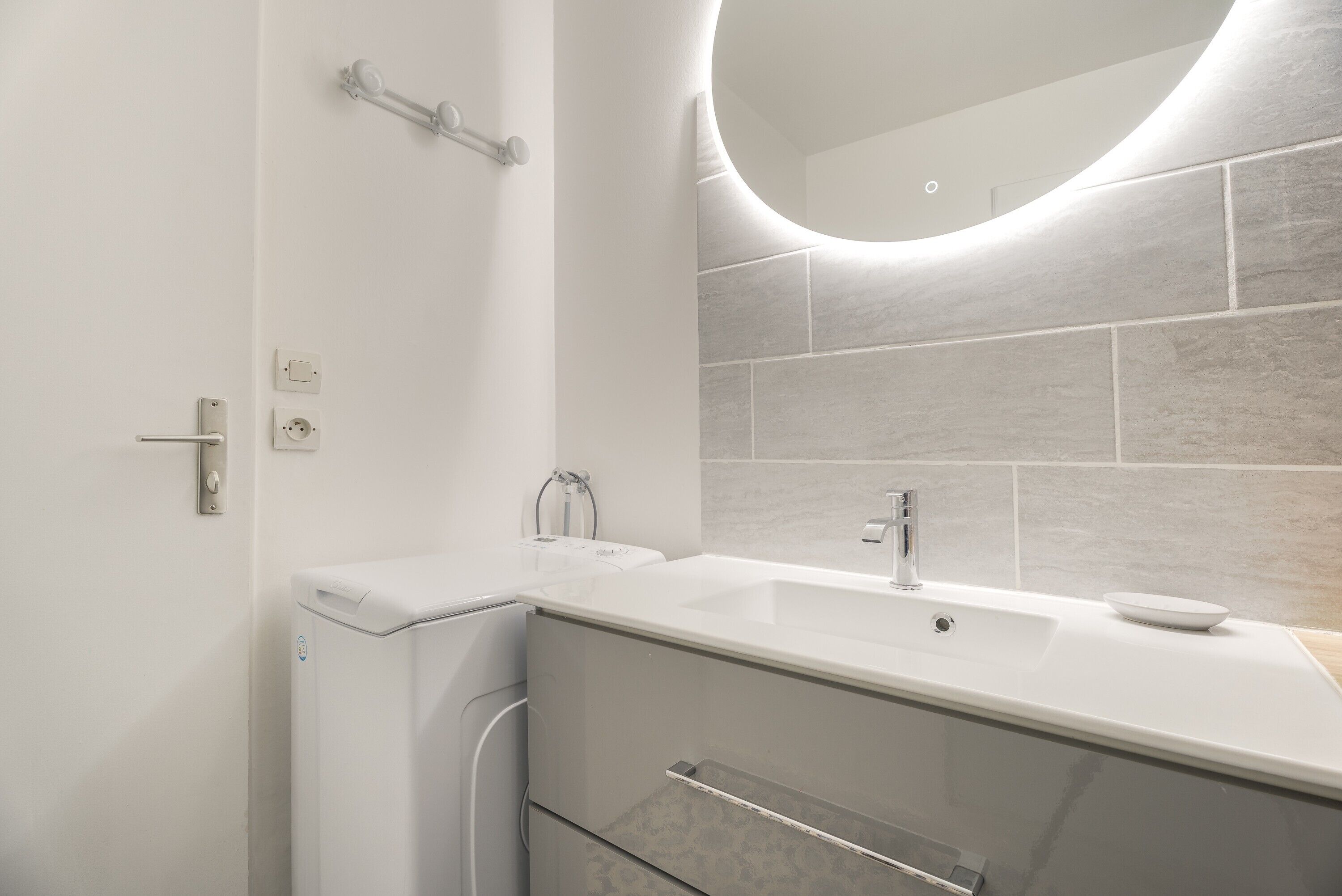 A modern bathroom with a white sink, a mirror, and a towel rack.