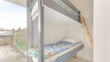 A bunk bed with a lower bunk, a ladder, and a window with a view of the outside.