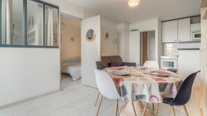 A compact living space with a dining area, kitchenette, and a bedroom.
