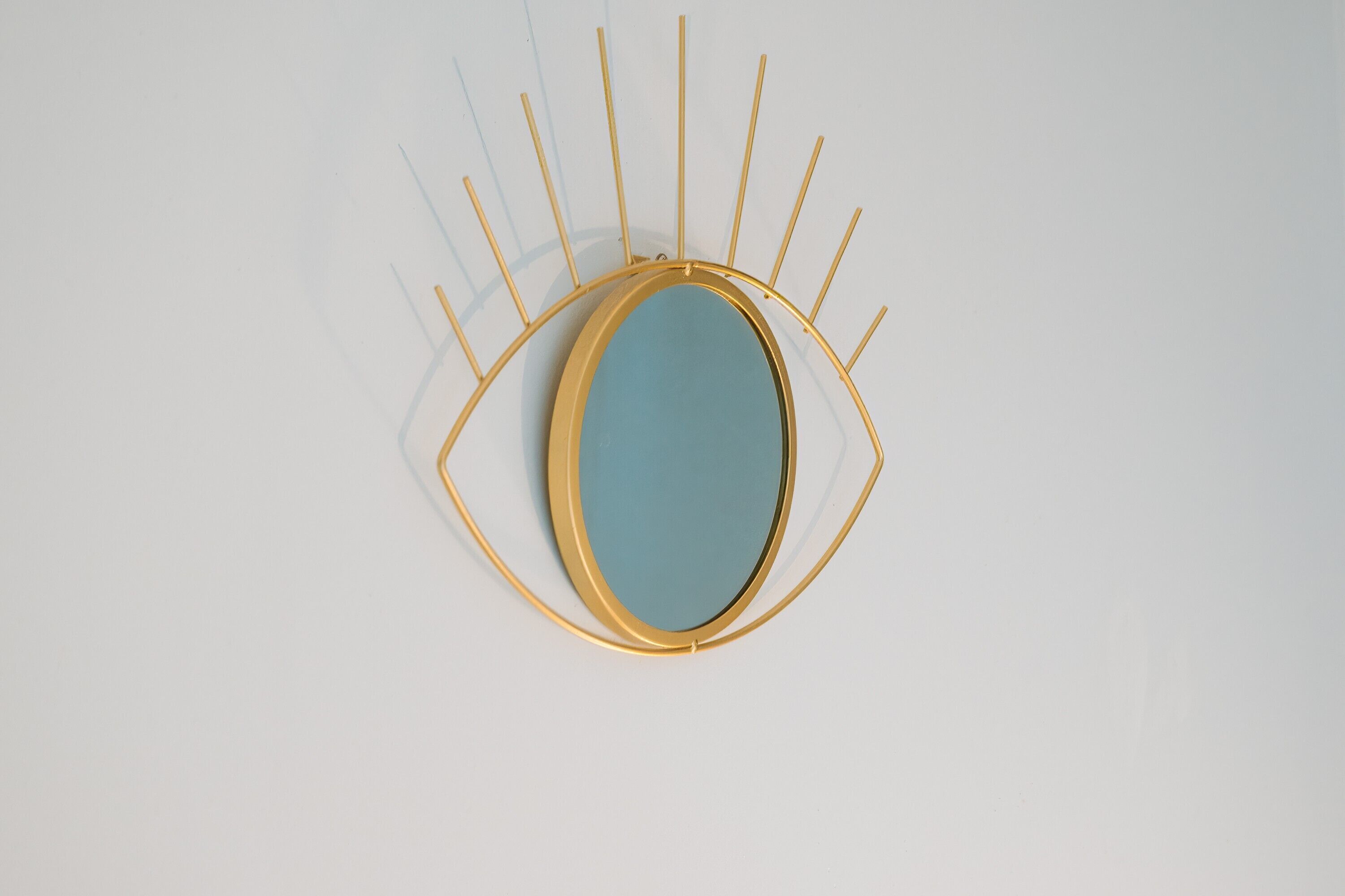 A wall-mounted mirror with a gold frame and a blue center.