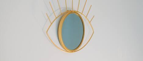 A wall-mounted mirror with a gold frame and a blue center.
