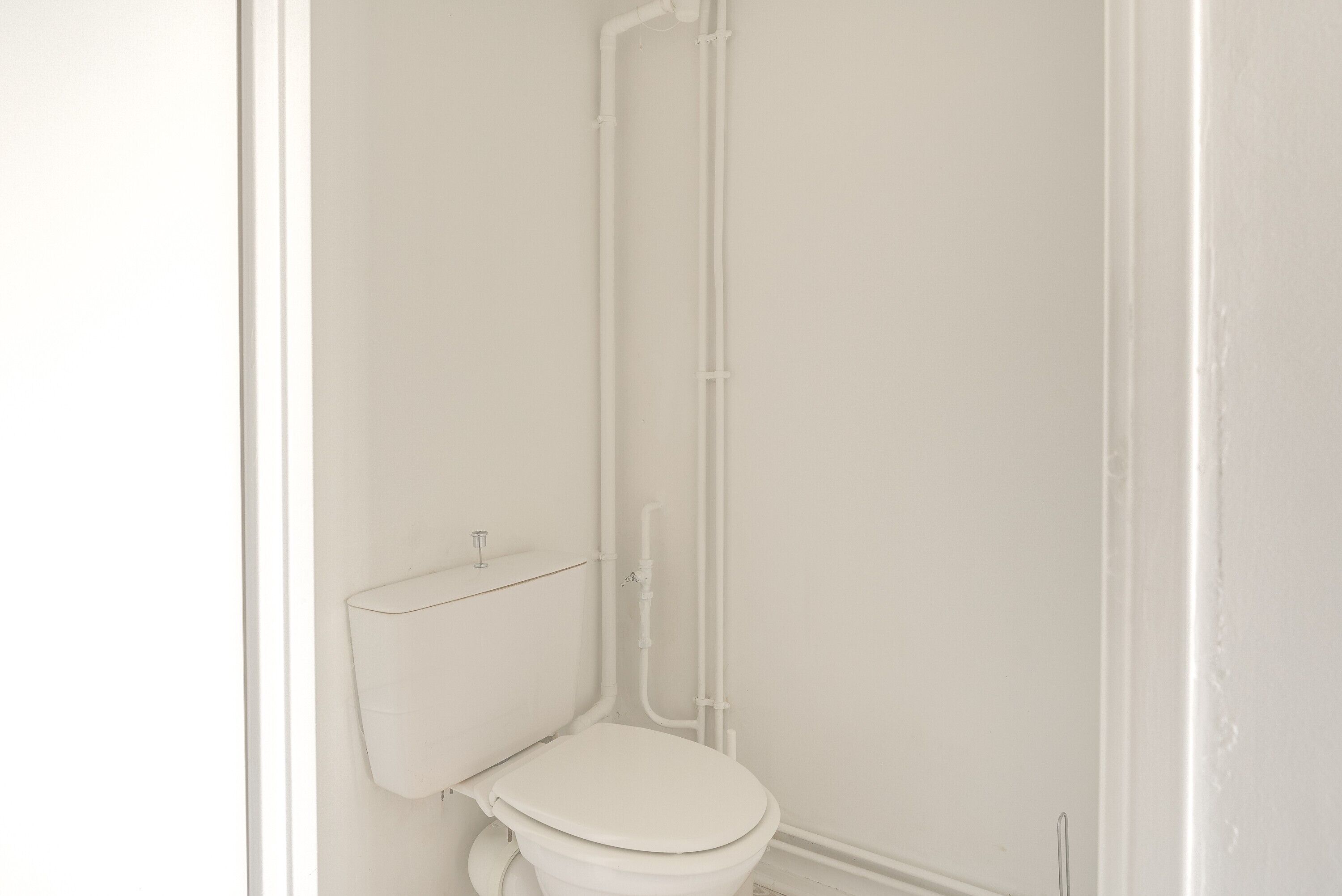 Un baño blanco con inodoro, ducha y lavamanos.