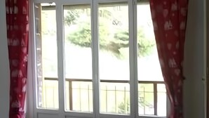 Une pièce avec une grande fenêtre, une chaise, une table et un lit.