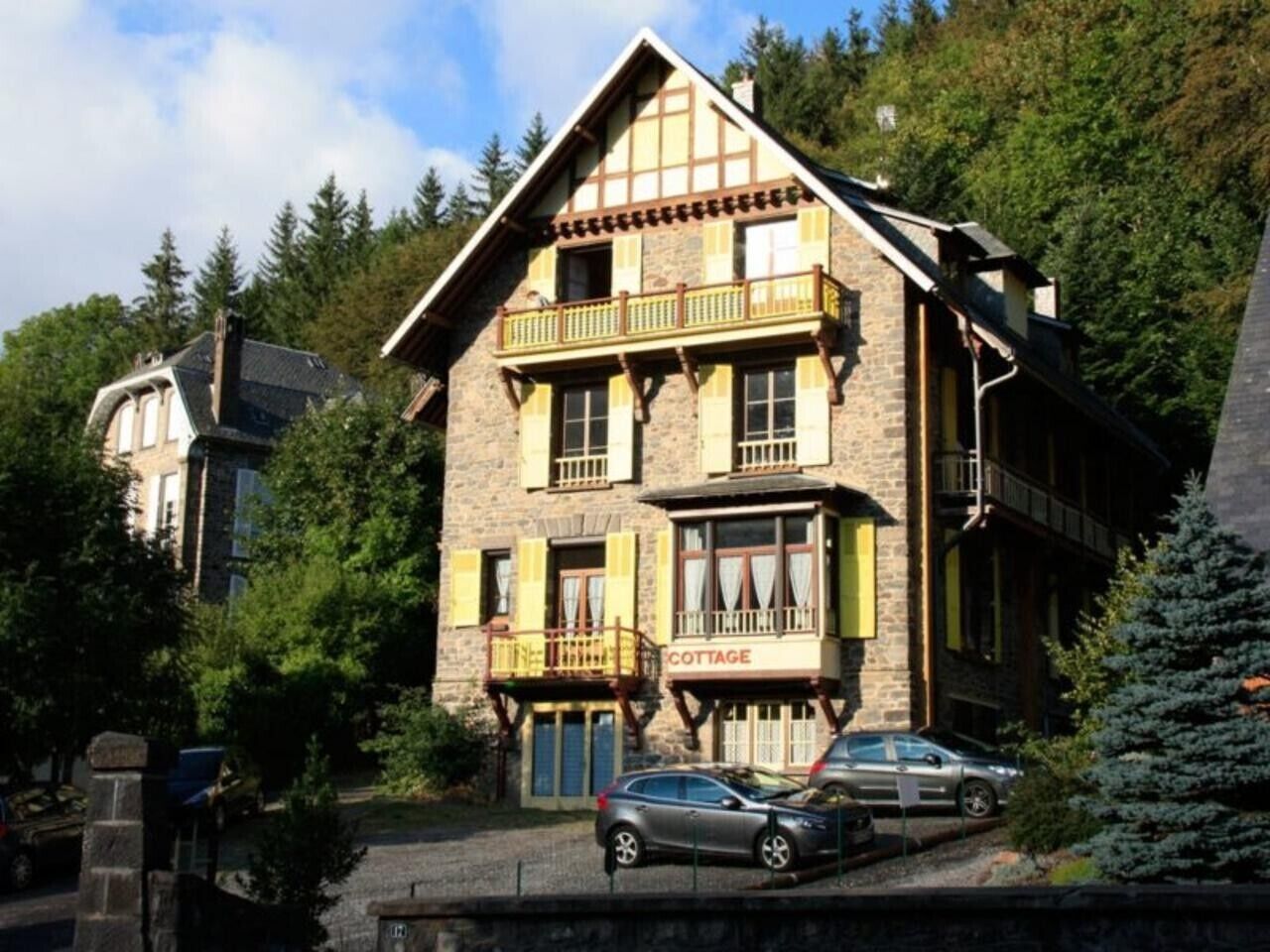 Un bâtiment en pierre avec une enseigne indiquant « COTTAGE » et un balcon.