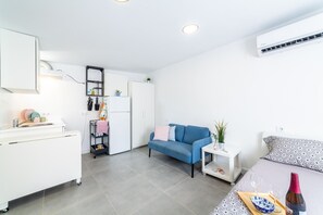 A compact living space with a kitchenette, a sofa, a small table, and a bed.