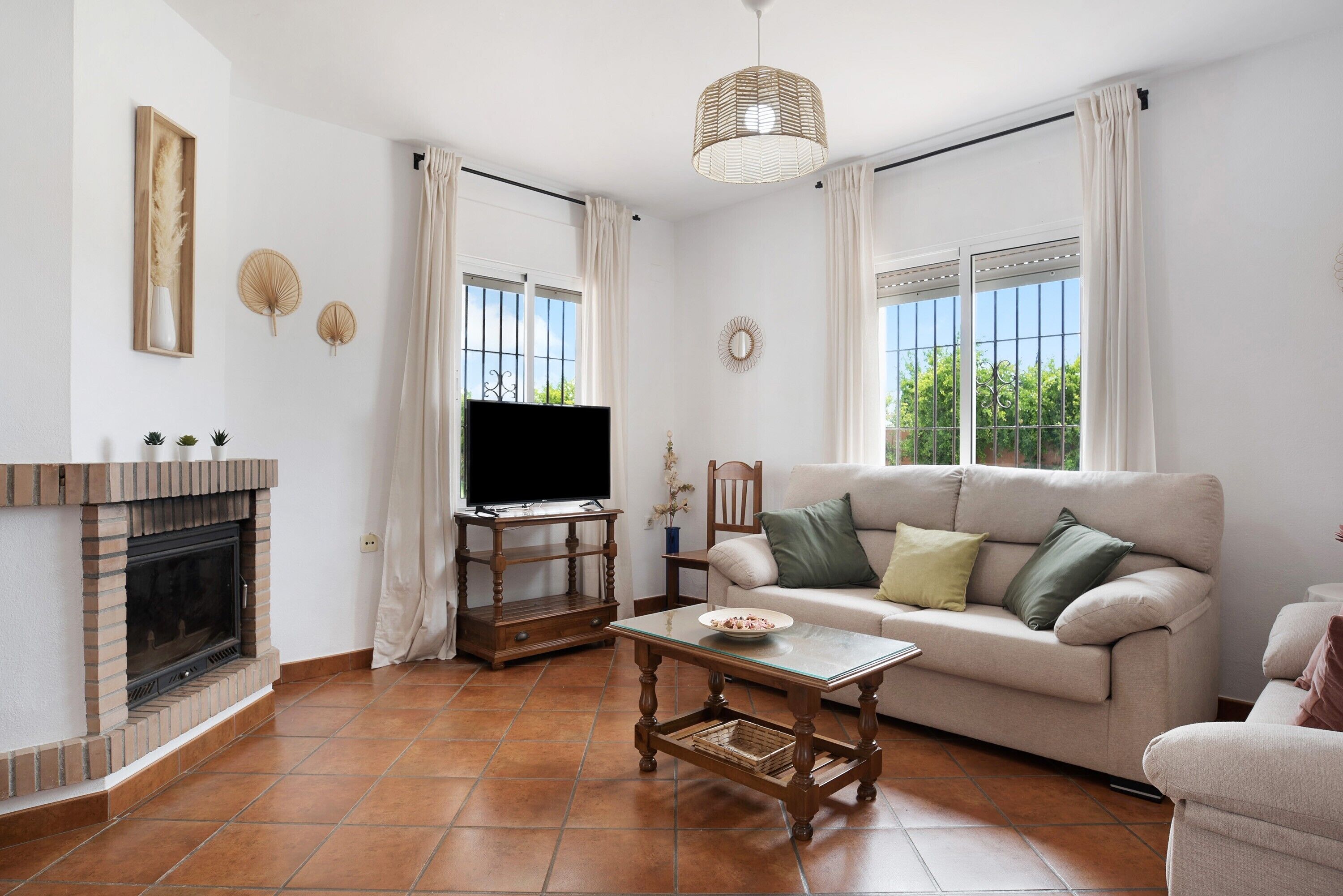 A living room with a fireplace, television, sofa, and a table.