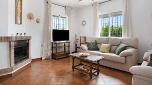 Una sala de estar con chimenea, televisor, sofá y una mesa.