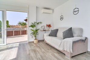 Un salon moderne avec un canapé, une plante en pot et des œuvres d’art décoratives accrochées au mur.