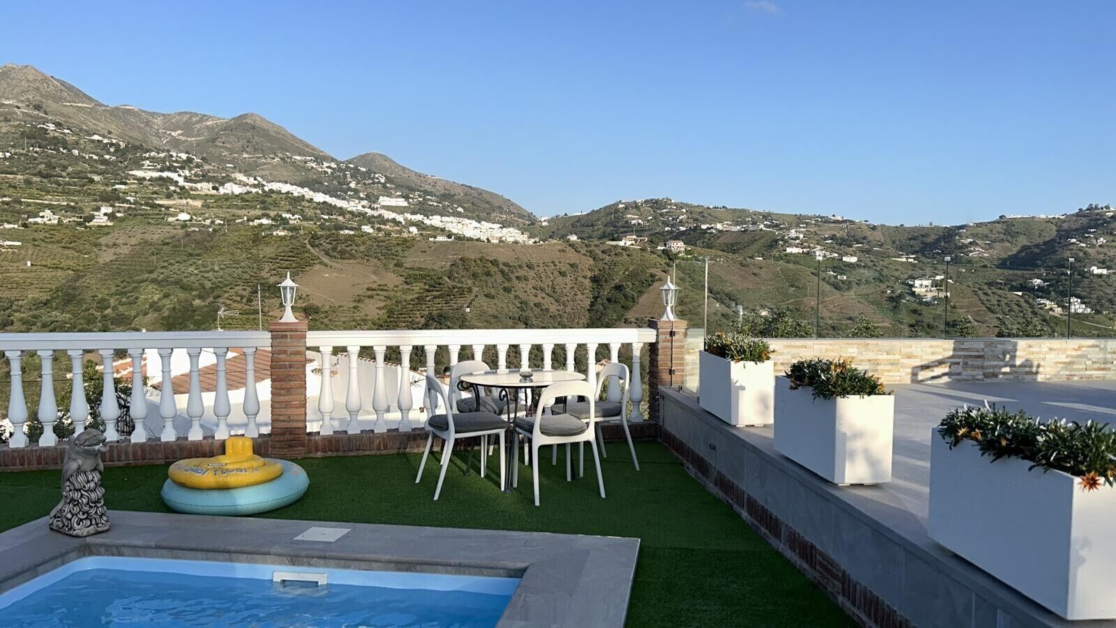 Una terraza en la azotea con piscina, mobiliario exterior y vistas a las colinas circundantes.
