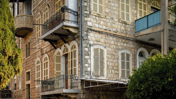Um edifício de pedra com vários andares, janelas em arco e varandas.