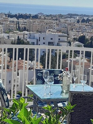 Une terrasse avec une table dressée pour deux personnes, offrant une vue sur le paysage urbain de la côte.