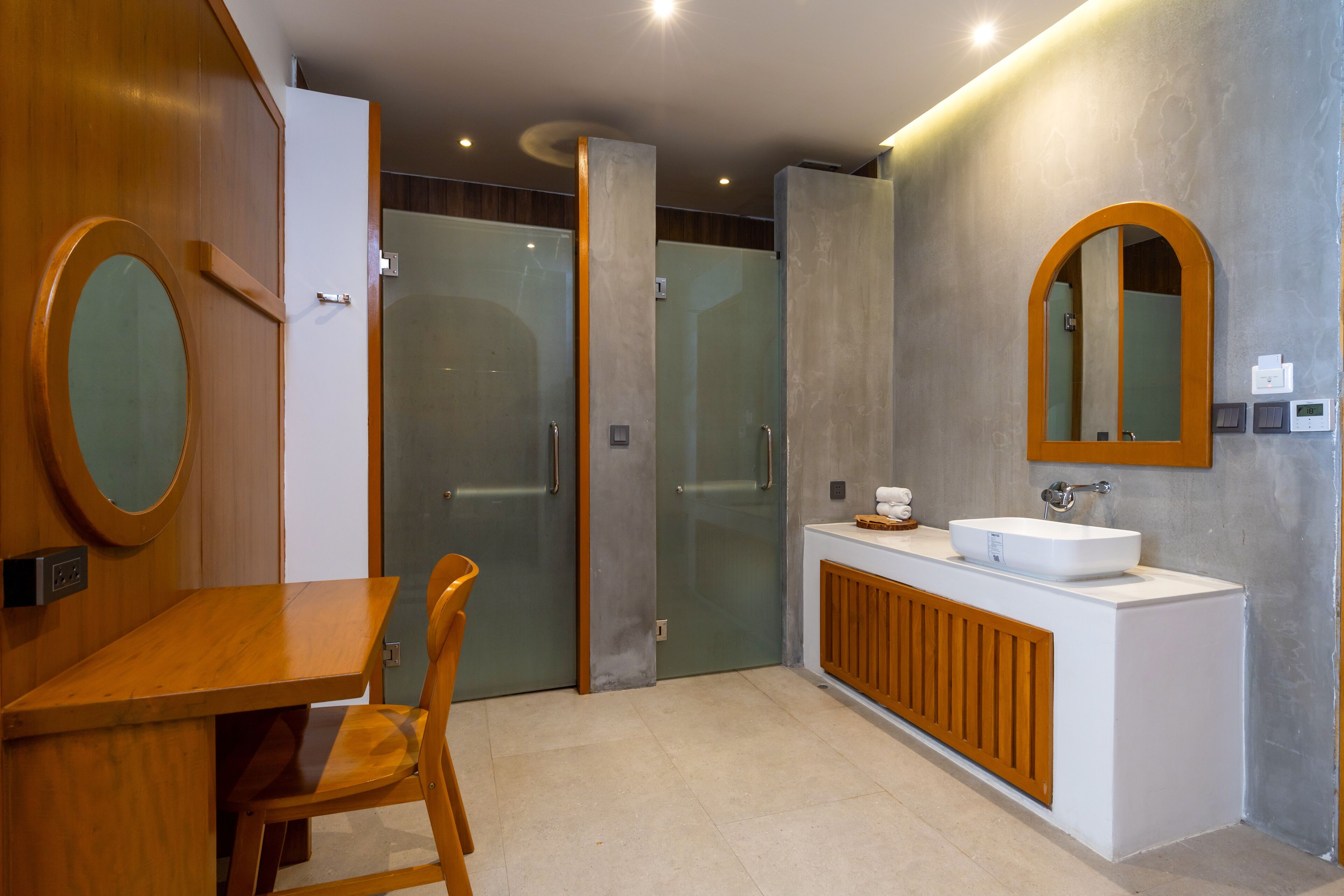 A modern bathroom with a wooden vanity, a round mirror, and a built-in sink.