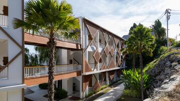 A modern building with a geometric facade, balconies, and a palm tree.