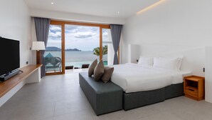 Una habitación de hotel moderna con una cama grande, un televisor y vistas al mar.