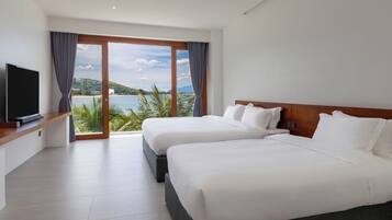 Une chambre d’hôtel avec deux lits, une télévision et une grande fenêtre donnant sur la mer.