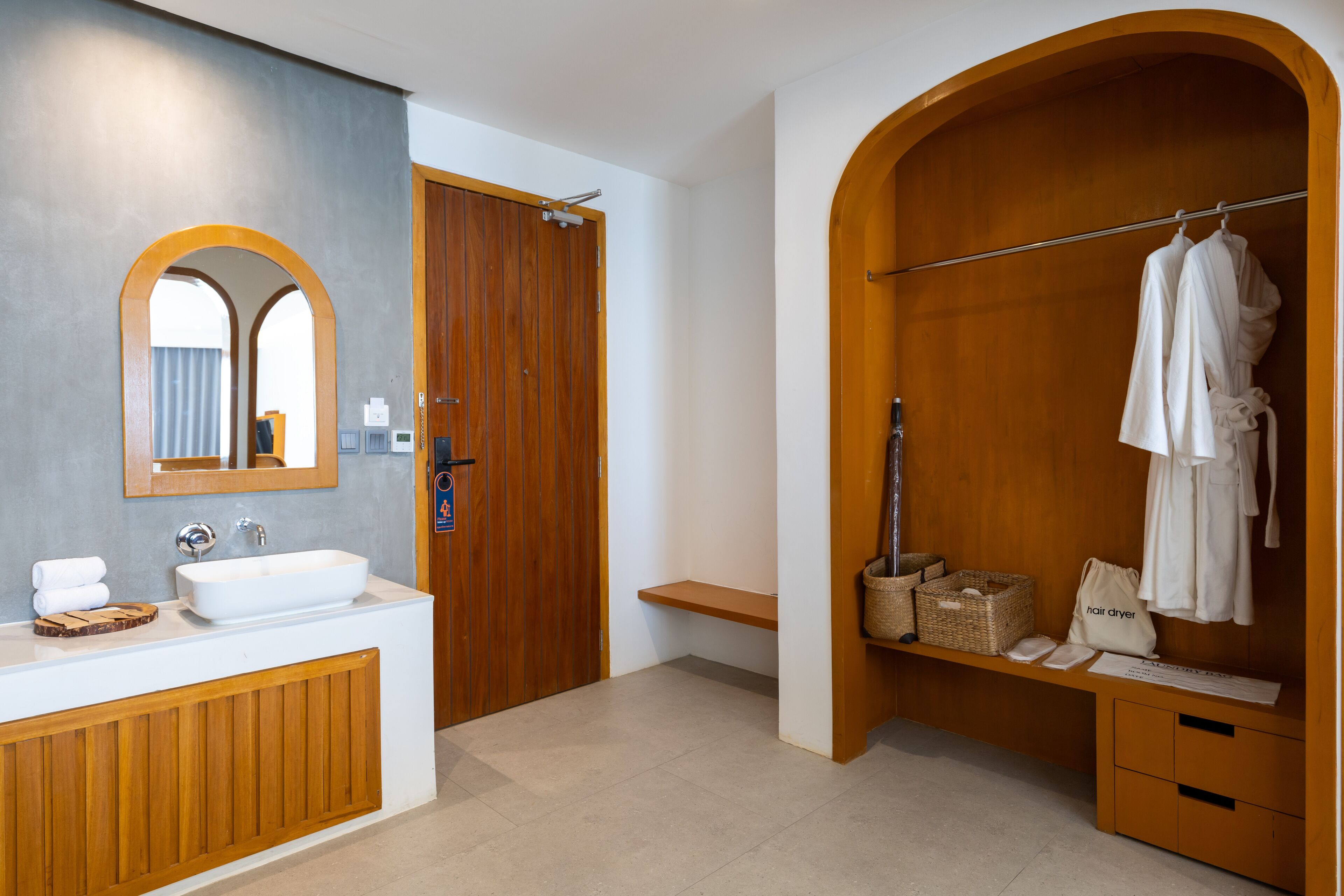 A modern bathroom with a wooden vanity, a large mirror, and a walk-in shower with a wooden arch.