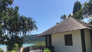 A coastal building with a tiled roof, a wooden deck, and a stone wall. - Saujana Private Villas (Langkawi)