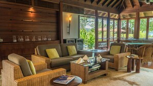 A cozy lounge area with wicker furniture, a pool table, and a view of greenery outside. - Saujana Private Villas (Langkawi)
