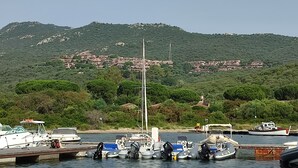 A marina with boats docked, a hill with buildings in the background, and a clear sky. - Elegant and spacious apartment with terrace and gulf view in Costa Smeralda  (Olbia)