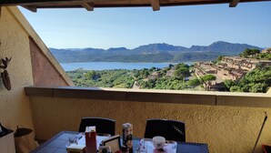A balcony with a table set for two, overlooking a scenic view of a lake and mountains. - Elegant and spacious apartment with terrace and gulf view in Costa Smeralda  (Olbia)
