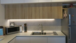 A modern kitchen with white cabinets, a stainless steel sink, and a microwave. - Elegant and spacious apartment with terrace and gulf view in Costa Smeralda  (Olbia)