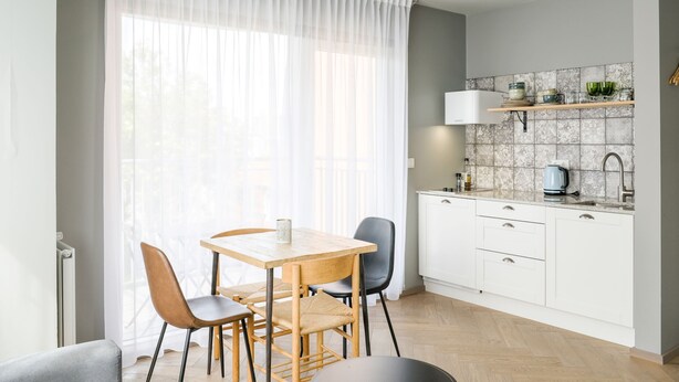 A modern kitchen with white cabinets, a wooden dining table, and a large window with sheer curtains. - Saga Studio for 4 guests in Downtown Hallgrímur (Reykjavík)