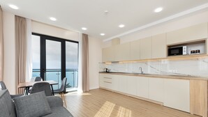 Una cocina moderna con armarios blancos, encimera de madera y microondas integrado.