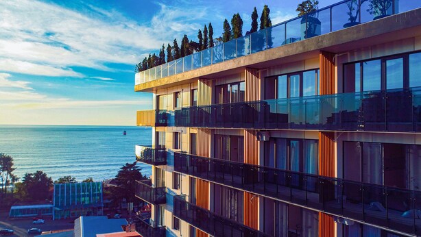 Un hotel moderno de varios pisos con balcones que dan a una masa de agua.