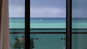 Vista a través de una ventana que muestra una escena costera con un barco en el agua.