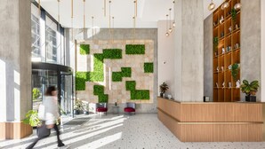 A modern lobby with a reception desk, seating area, and a wall with green planters. - Next Green Aparthotel Official (Batumi)