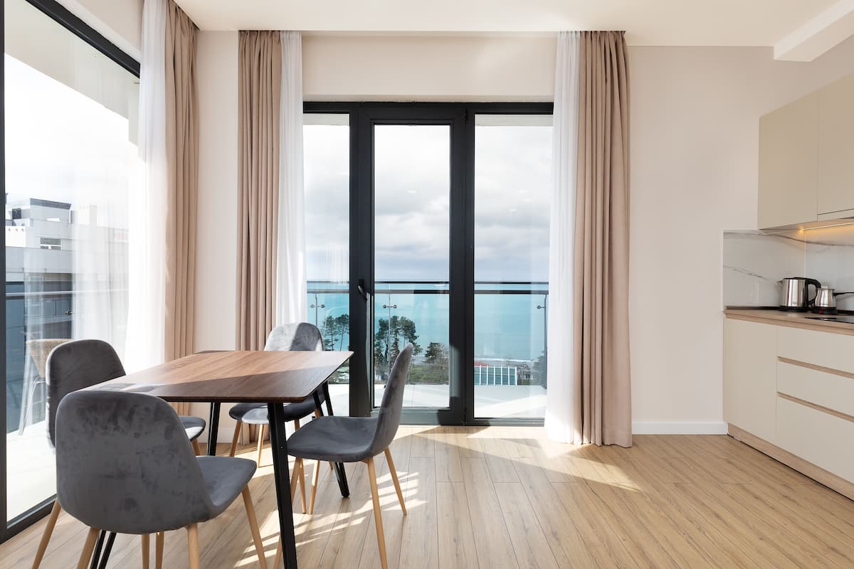 A modern apartment with a dining area, kitchen, and a balcony with a city view.