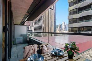 Un balcon aménagé avec un coin repas, comprenant une table, des chaises et un pot de fleurs.