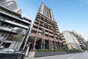 A modern high-rise building with multiple balconies, large windows, and a prominent entrance. - Stylish & Modern 2BR Apt Near Victoria Market (Melbourne)
