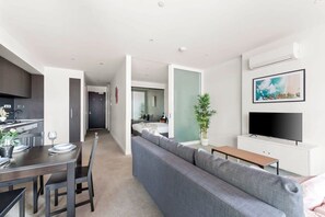 Un appartement moderne comprenant un coin repas, un salon avec un canapé et une télévision, ainsi qu’une cuisine.