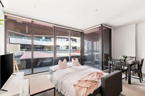A modern hotel room with a large bed, a desk, and a dining area. - Stylish & Modern 2BR Apt Near Victoria Market (Melbourne)
